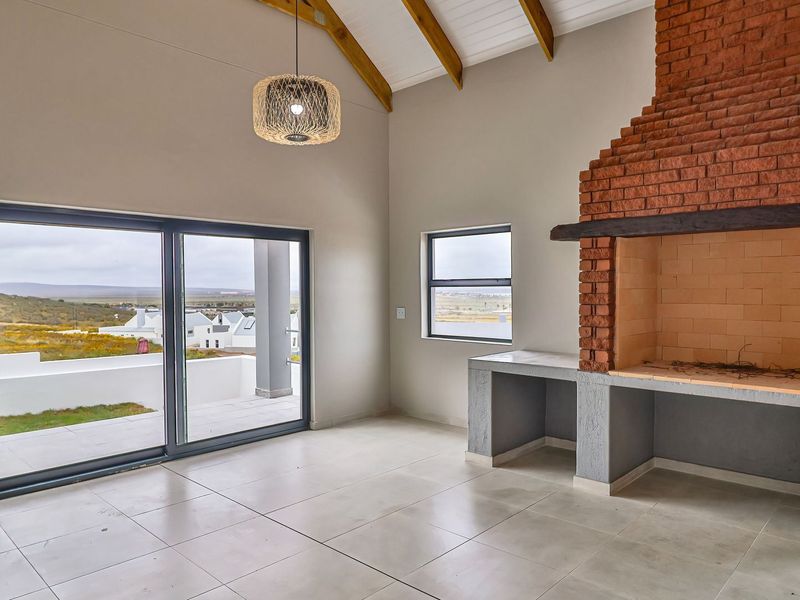 Spacious living area featuring a vaulted ceiling with exposed timber rafters, a large built-in brick fireplace, and sliding glass doors leading to a patio.