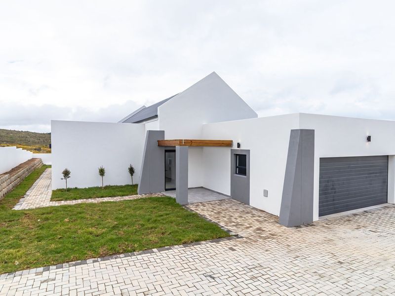 Modern contemporary home featuring a clean white facade, paved driveway, double garage, and a covered entrance with timber detailing.