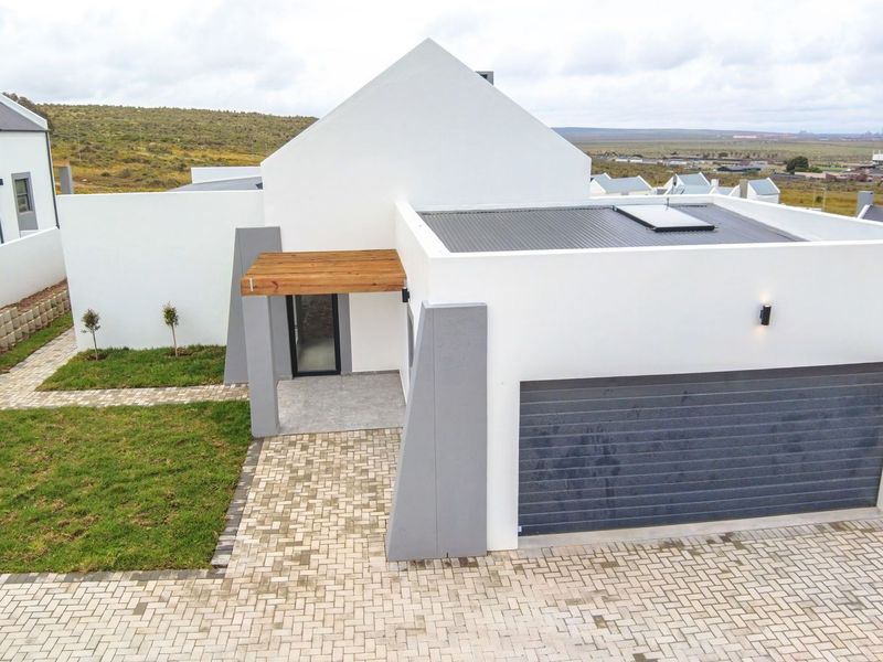 Modern architectural home featuring a clean white facade, timber entrance pergola, paved driveway, and integrated double garage in a well-maintained estate setting.