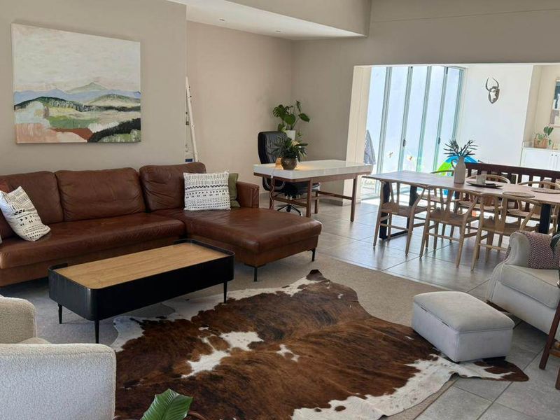 Spacious open-plan living and dining area featuring tiled floors, recessed lighting, and large sliding glass doors leading to the outdoor space.