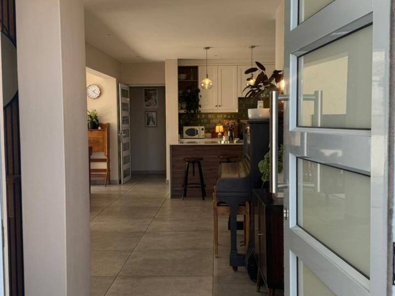 View from the entrance door looking into the open-plan living and kitchen area, featuring modern tiled flooring and recessed lighting.