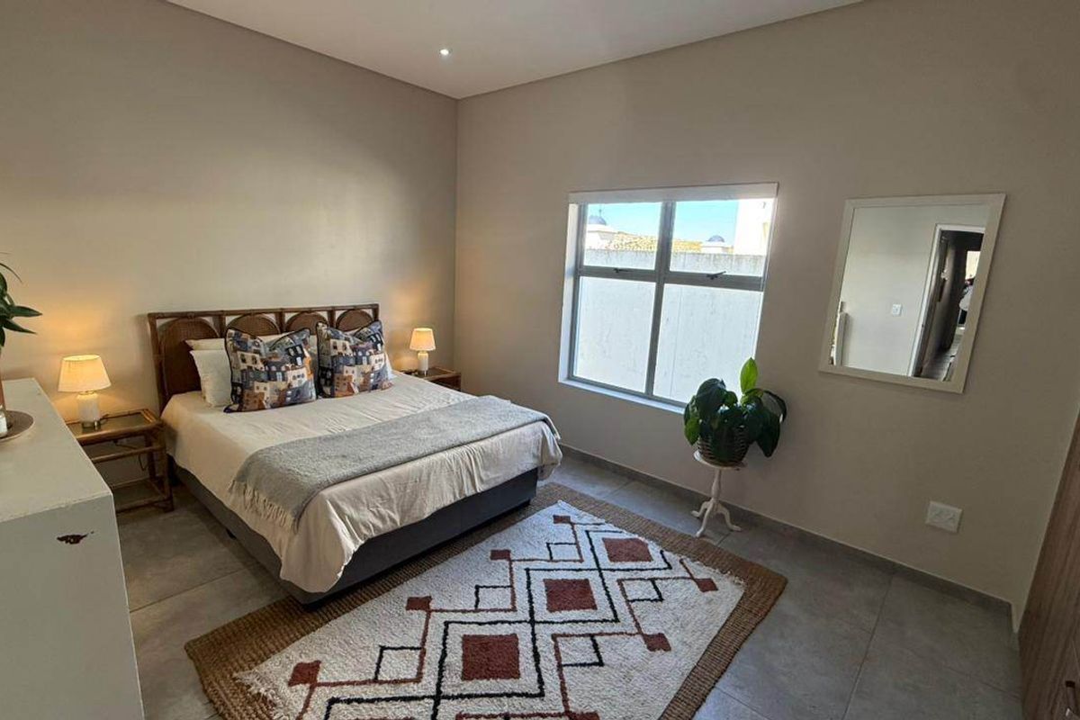 A well-maintained bedroom featuring neutral tiled flooring, recessed lighting, and a built-in wardrobe, offering a clean and functional living space.