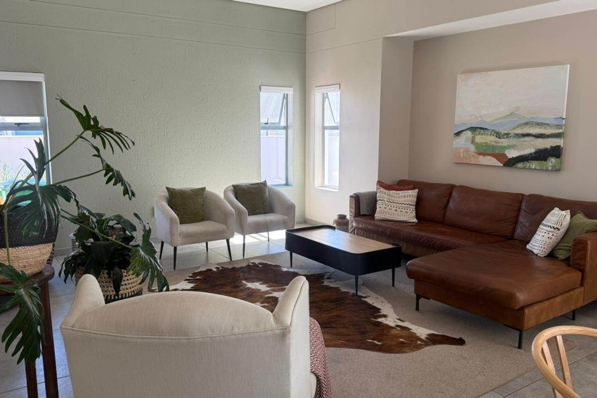 A bright and spacious living room featuring neutral wall tones, tiled flooring, and a recessed wall niche, offering a comfortable and well-maintained living space.