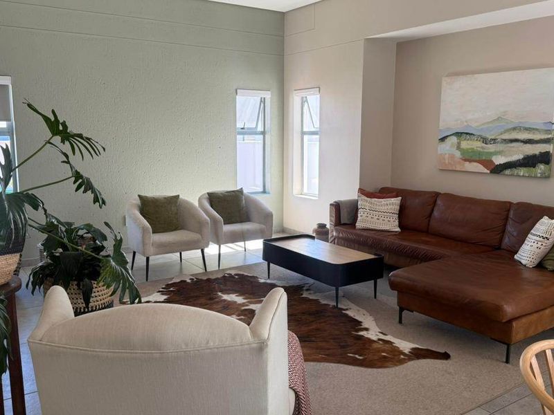 A bright and spacious living room featuring neutral wall tones, tiled flooring, and a recessed wall niche, offering a comfortable and well-maintained living space.
