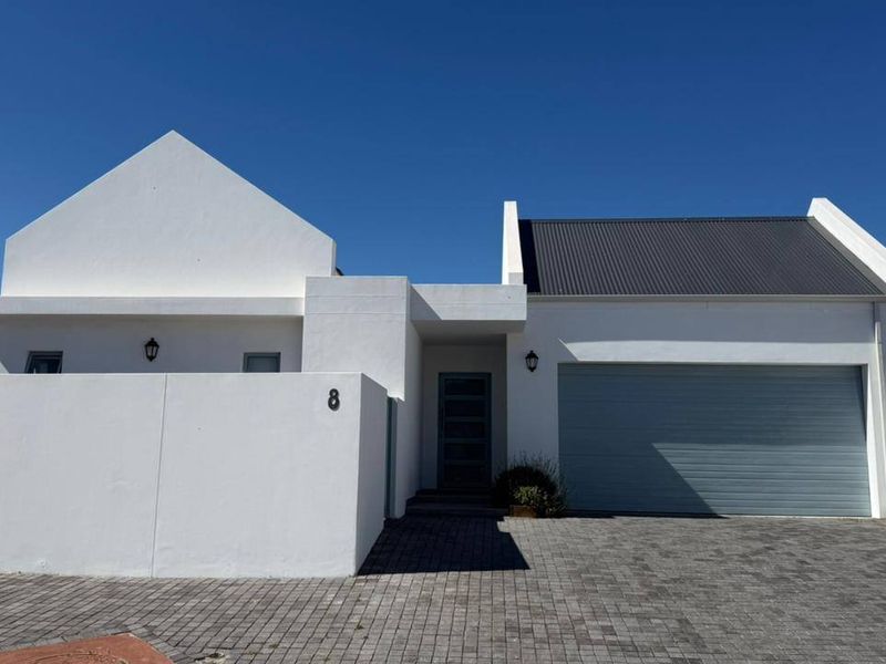 Front elevation of a modern house featuring a paved driveway, single garage, and clean white exterior walls.