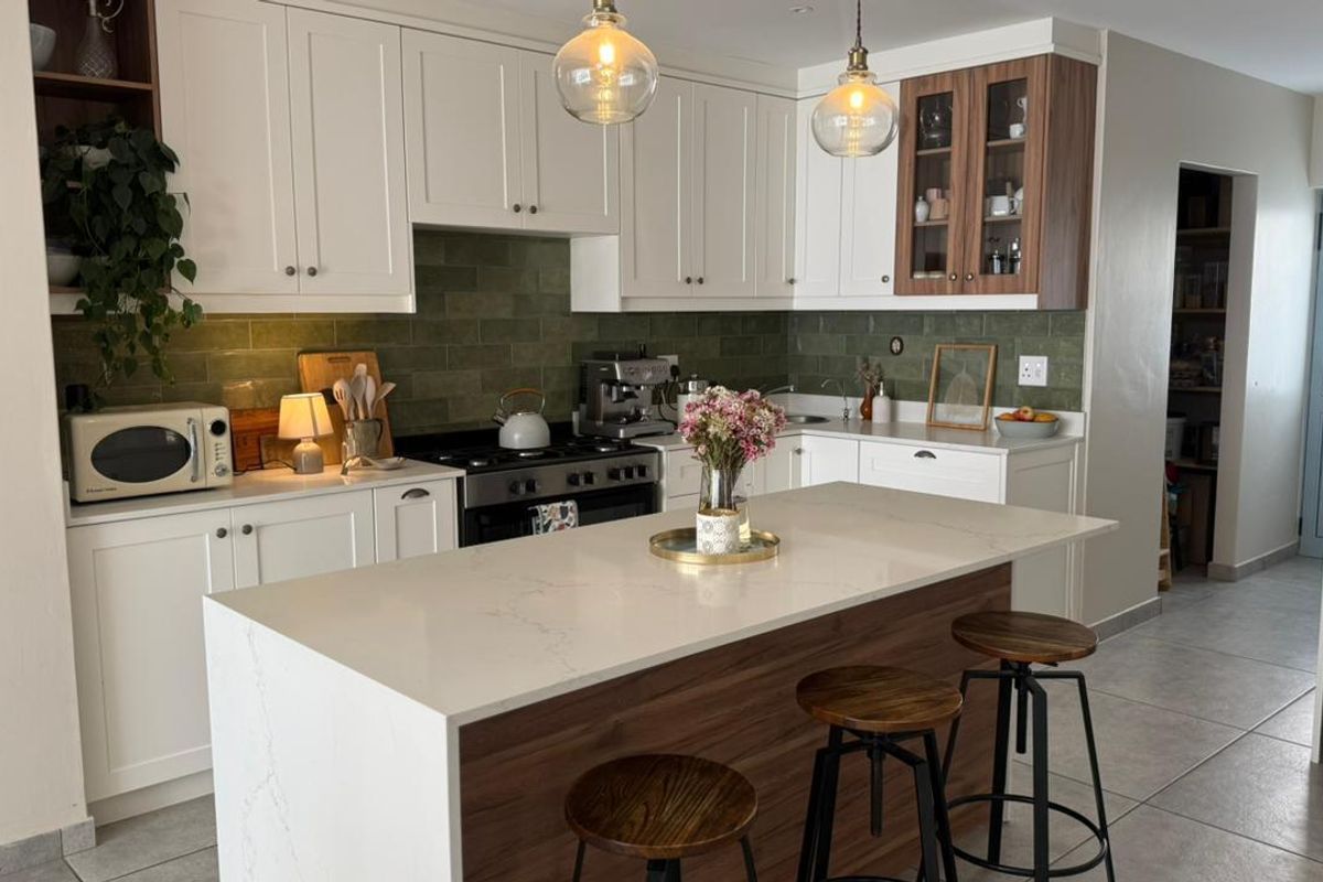Modern kitchen featuring white shaker cabinetry, quartz countertops, a central island, and a stylish green subway tile backsplash.