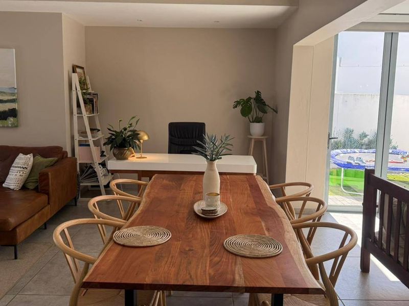 A bright open-plan living and dining area featuring tiled floors, recessed lighting, and large sliding glass doors that provide seamless access to the outdoor space.