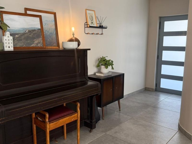 A bright and welcoming entrance hall featuring modern grey floor tiles and a contemporary frosted glass panel door.