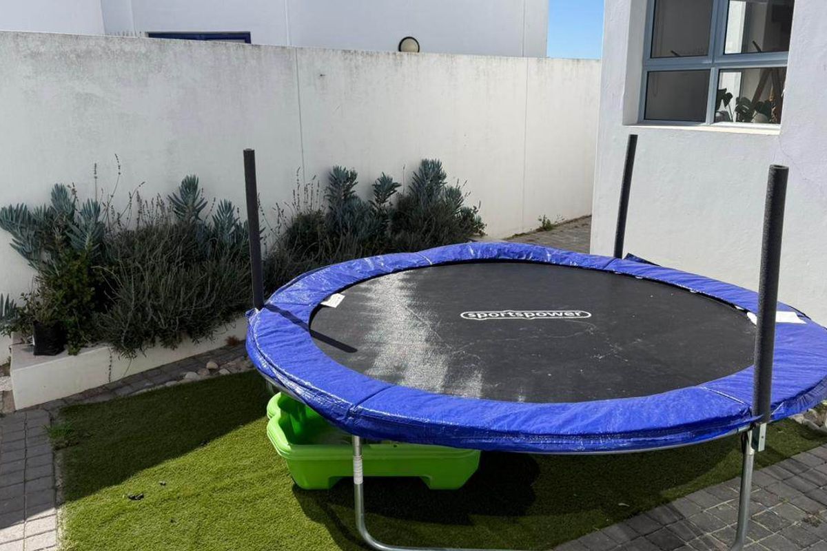 A small rear courtyard area featuring a paved section, artificial grass, and a perimeter boundary wall.