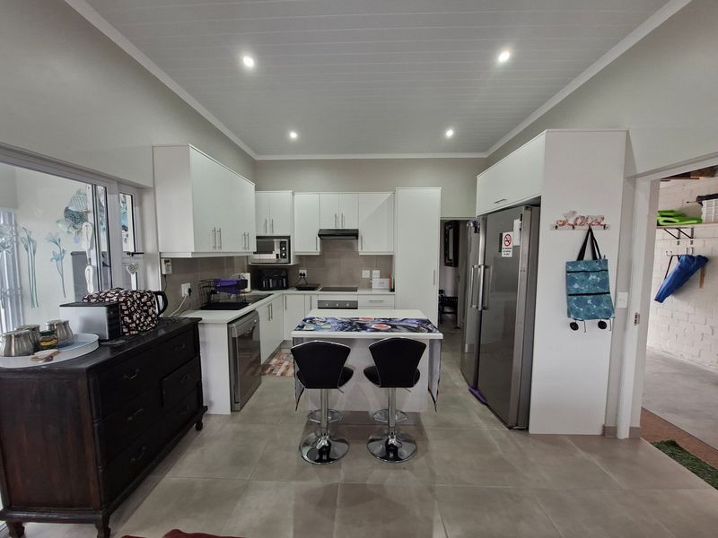 Modern kitchen featuring white cabinetry, a central island, built-in appliances, tiled flooring, and recessed lighting, offering a clean and functional cooking space.