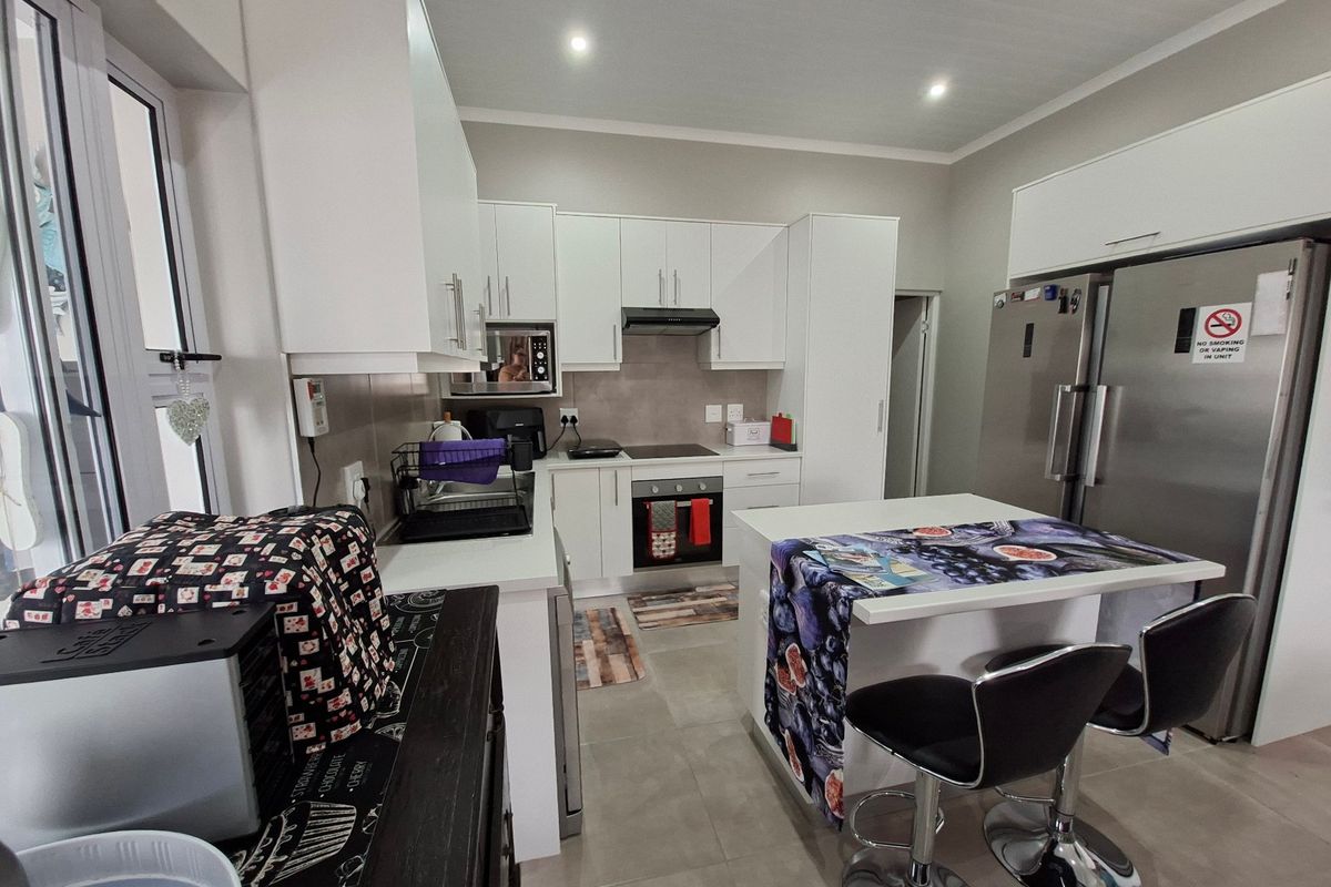 Modern kitchen featuring white cabinetry, stone countertops, integrated appliances including an oven and hob, and tiled flooring with recessed lighting.