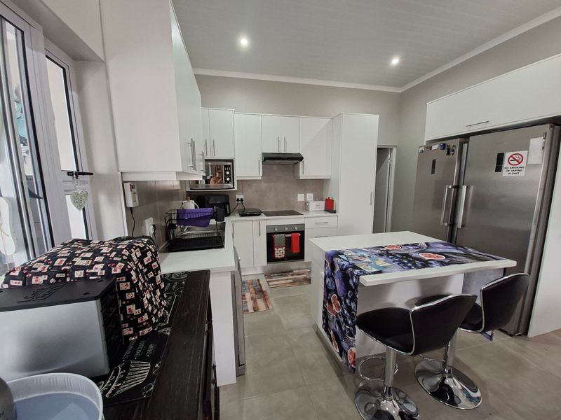 Modern kitchen featuring white cabinetry, stone countertops, integrated appliances including an oven and hob, and tiled flooring with recessed lighting.