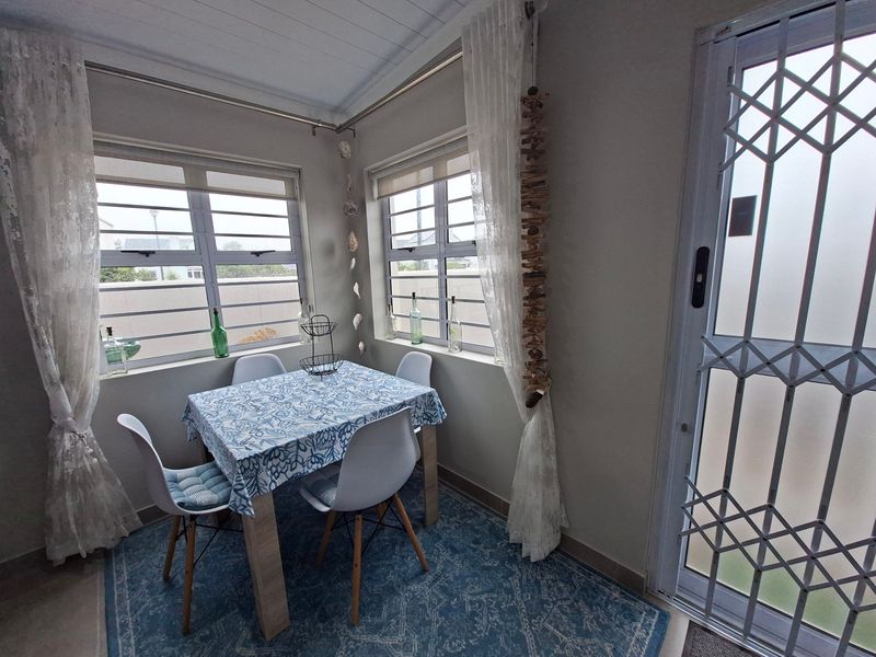 A bright dining area featuring aluminium windows, a security gate, and a timber-look ceiling, providing a functional space for meals.