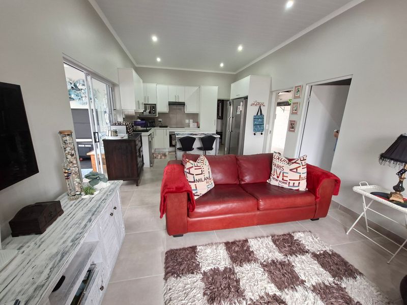 Open-plan living area featuring tiled floors, recessed lighting, and a functional kitchen with built-in cabinetry, seamlessly connecting to the outdoor patio space.