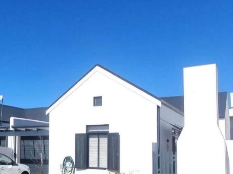 A well-maintained front exterior view of a modern house featuring a prominent external chimney, clean white facade, and dark window shutters.