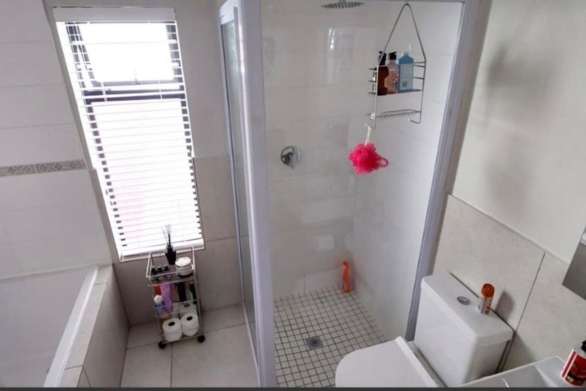A functional bathroom featuring a glass-enclosed shower, tiled walls, and a standard toilet, offering a clean and practical layout.