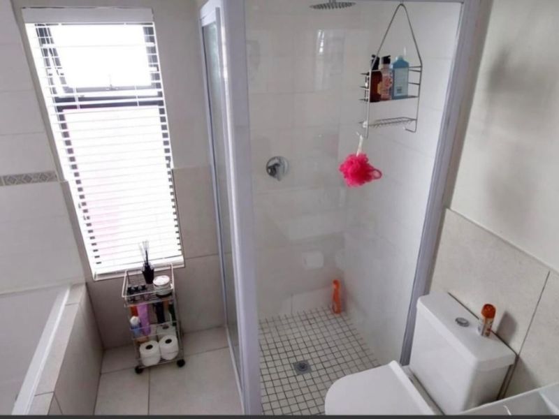A functional bathroom featuring a glass-enclosed shower, tiled walls, and a standard toilet, offering a clean and practical layout.