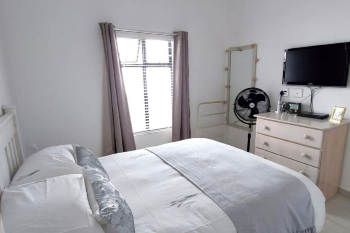 A functional bedroom featuring neutral walls, tiled flooring, and a window providing natural light.