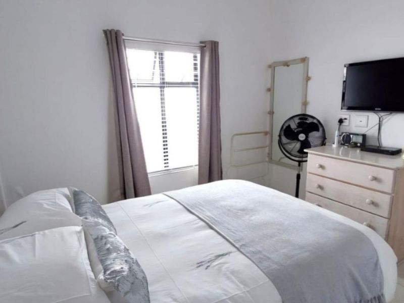 A functional bedroom featuring neutral walls, tiled flooring, and a window providing natural light.