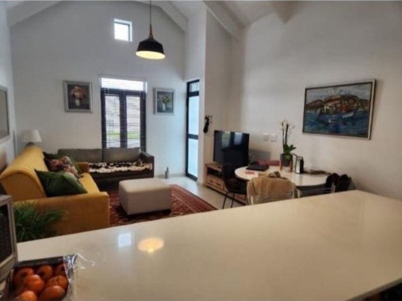 An open-plan living area featuring a high vaulted ceiling, modern pendant lighting, and a kitchen island, creating a bright and spacious atmosphere.