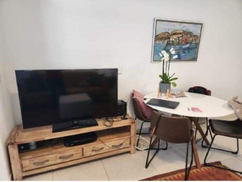 A living area featuring tiled flooring and neutral wall finishes, providing a functional space for relaxation and dining.
