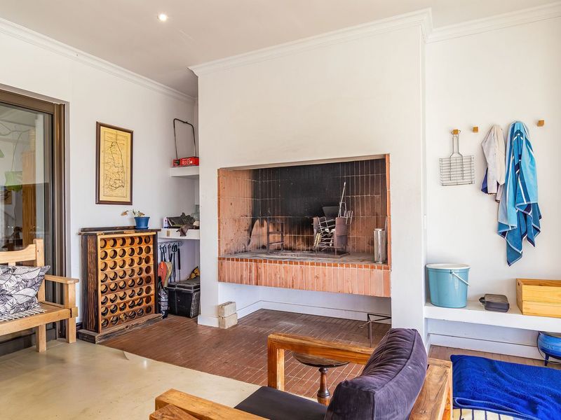 Covered patio area featuring a built-in brick braai, tiled flooring, and sliding glass doors providing access to the interior living space.
