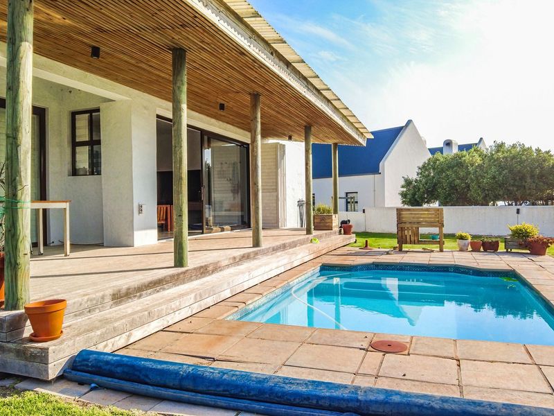 Outdoor entertainment area featuring a swimming pool, paved surround, and a covered timber deck with sliding door access to the main living space.