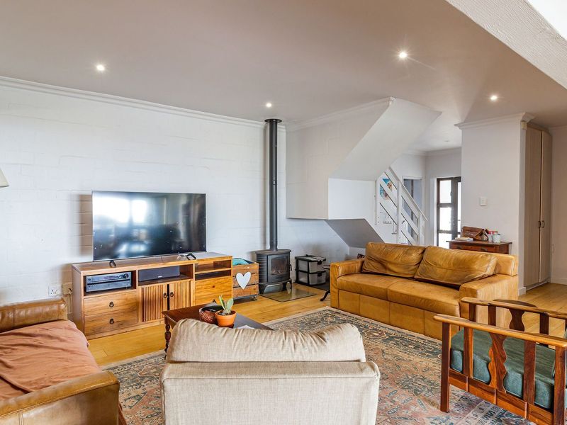 Spacious living room featuring timber flooring, a built-in wood-burning fireplace, and a staircase, creating a warm and inviting atmosphere.