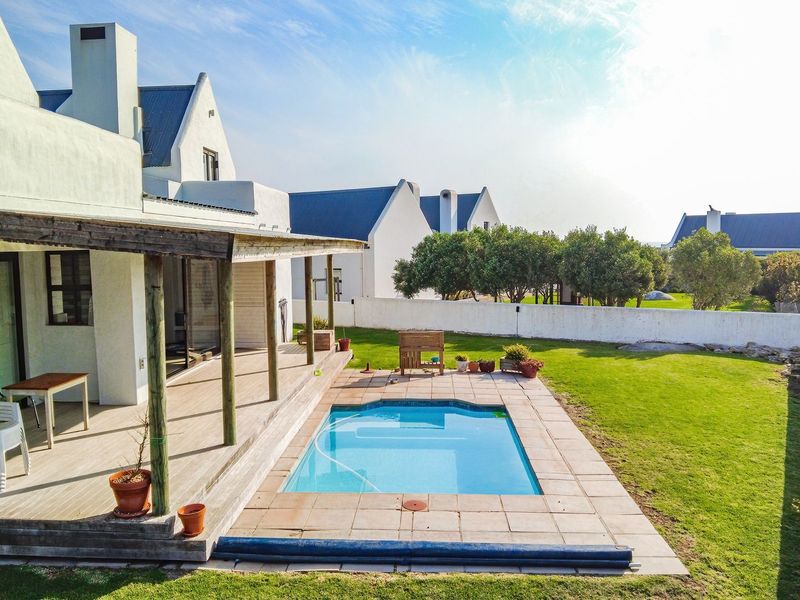 Rear view of the property featuring a swimming pool, paved pool surround, and a covered timber deck patio area.