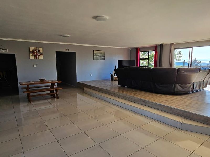 Spacious open-plan living area featuring a raised timber platform, tiled flooring, and large sliding glass doors that provide natural light and outdoor access.