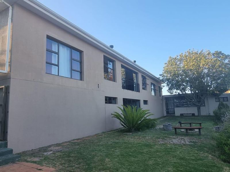 Rear view of the property showing the exterior facade, garden area, and installed water tank.