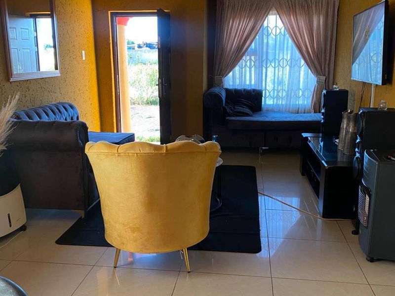 A living room featuring tiled flooring, coved ceilings, and direct access to the exterior through a security door.