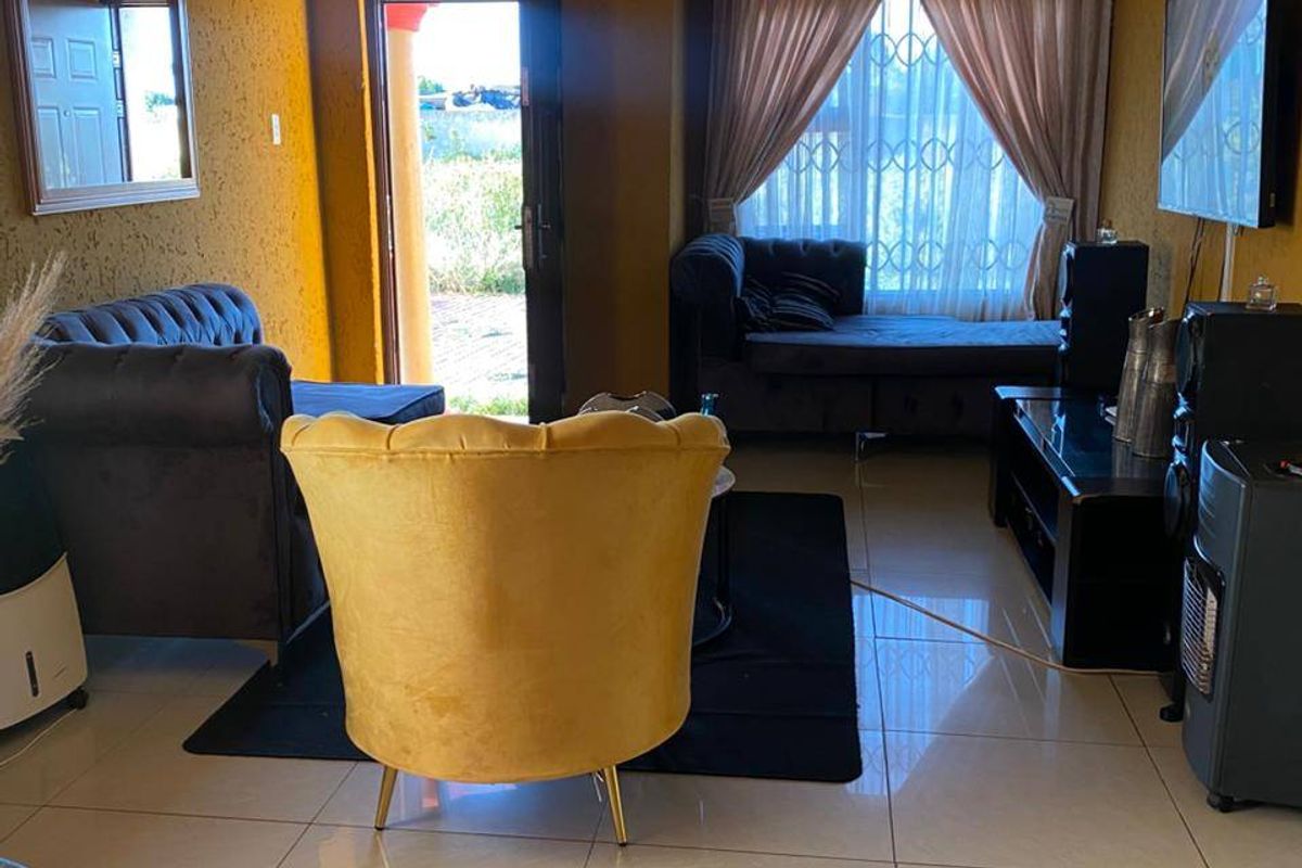 A living room featuring tiled flooring, coved ceilings, and direct access to the exterior through a security door.