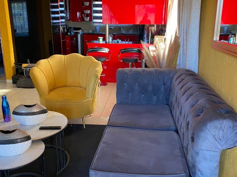 Open plan living area featuring a vibrant red kitchen with glossy cabinetry and tiled flooring, seamlessly connected to the lounge space.