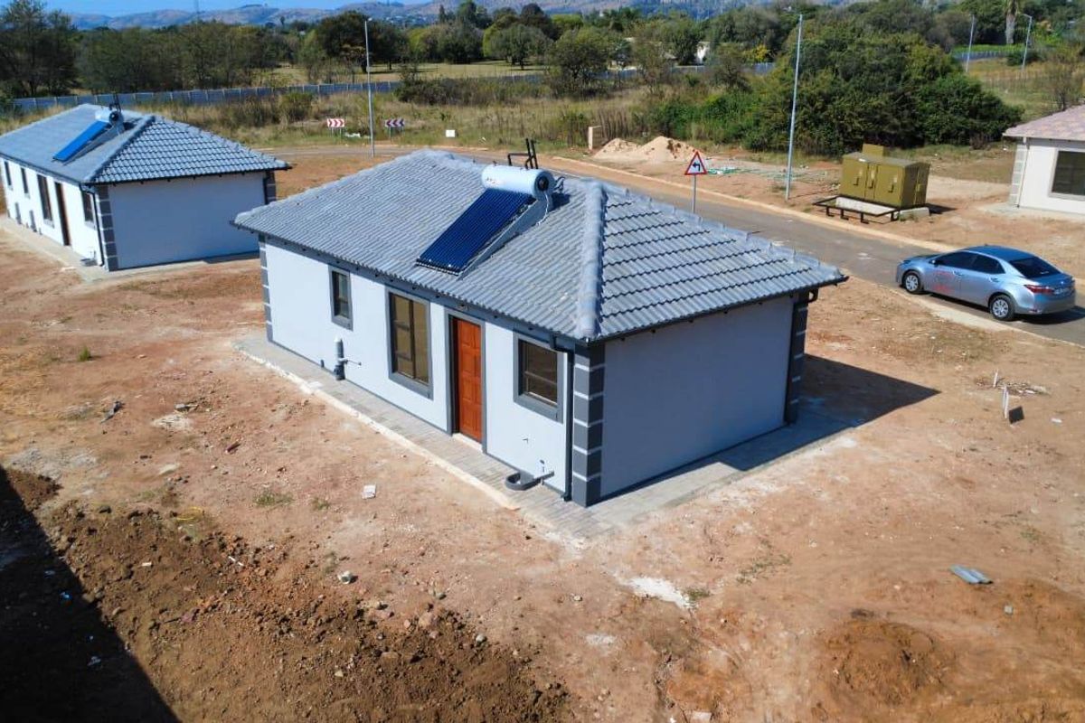 Aerial view of a modern single-story residential house featuring a tiled roof and an integrated solar water heating system.