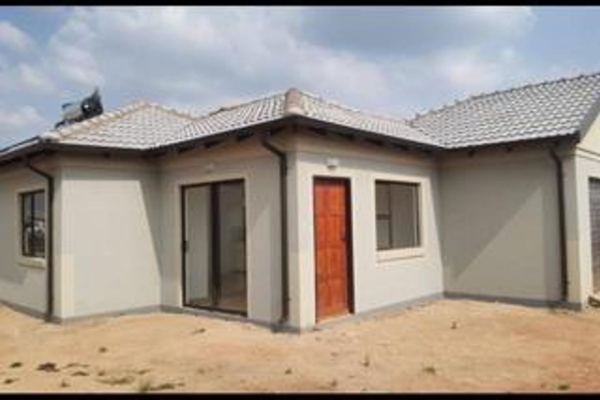 Rear view of a modern single-story house featuring a tiled roof, solar water heating system, and sliding glass door access.