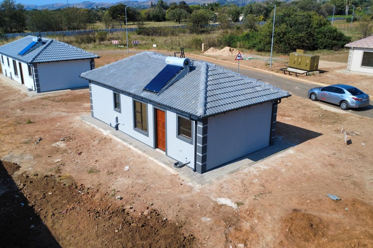 Aerial view of a modern detached house featuring a tiled roof with an integrated solar water heating system and paved perimeter.