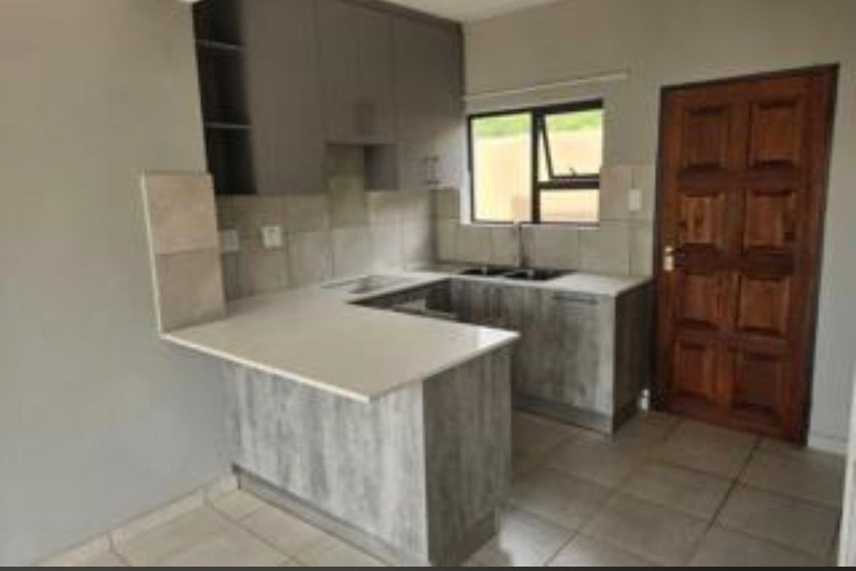 A functional kitchen featuring modern grey cabinetry, stone countertops, a double sink, and tiled flooring, providing a clean and practical workspace.