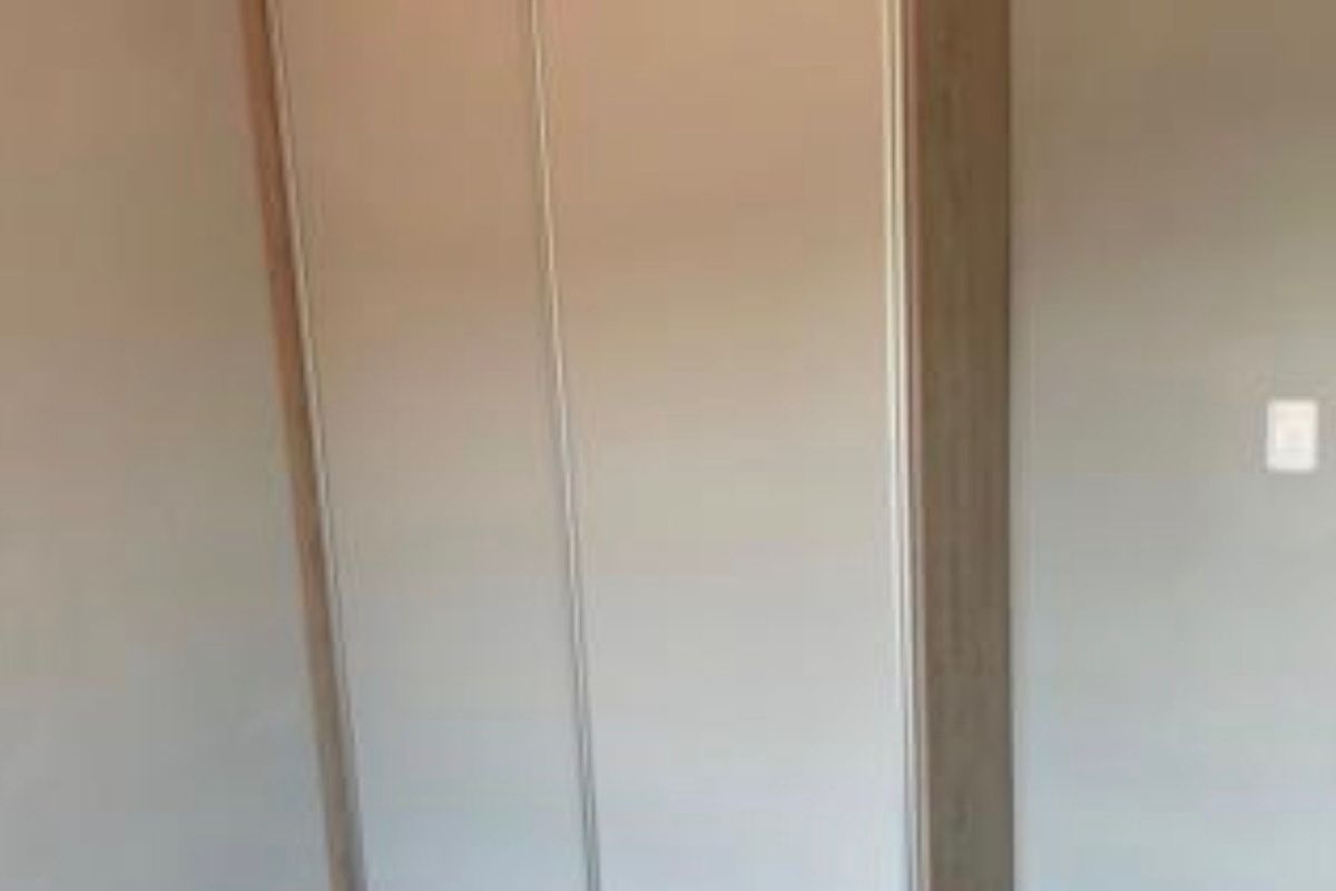 A bedroom featuring a built-in wardrobe with light wood-tone trim and neutral-toned doors.