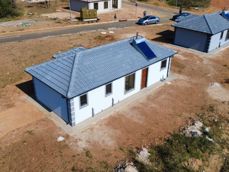 Aerial view of a newly constructed single-story residential house featuring a tiled roof and integrated solar water heating system.