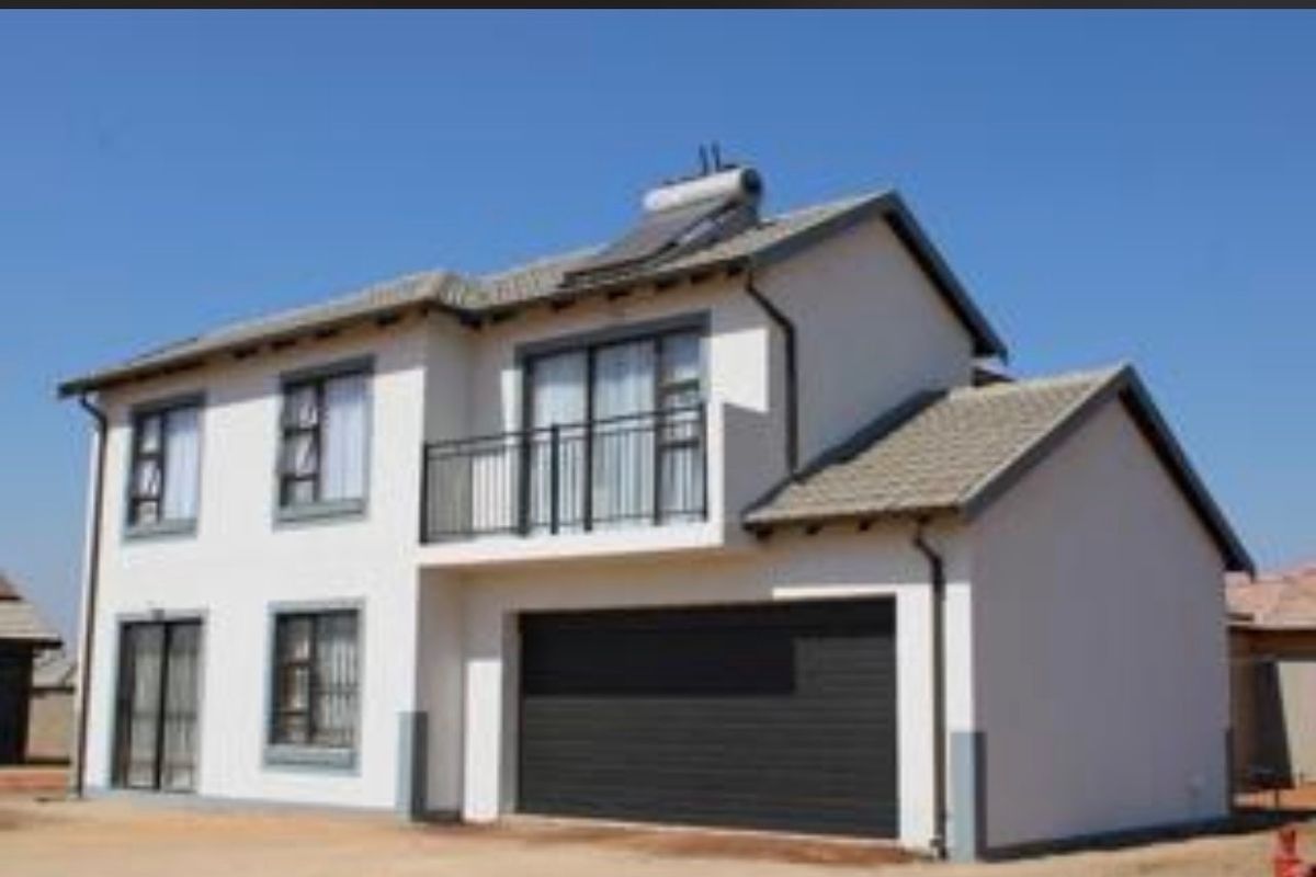 A modern double-storey residential house featuring a tiled roof, solar water heating system, balcony, and a double garage.