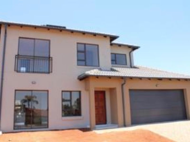 A modern double-storey residential home featuring a tiled roof, integrated double garage, and balcony, set on a paved driveway.