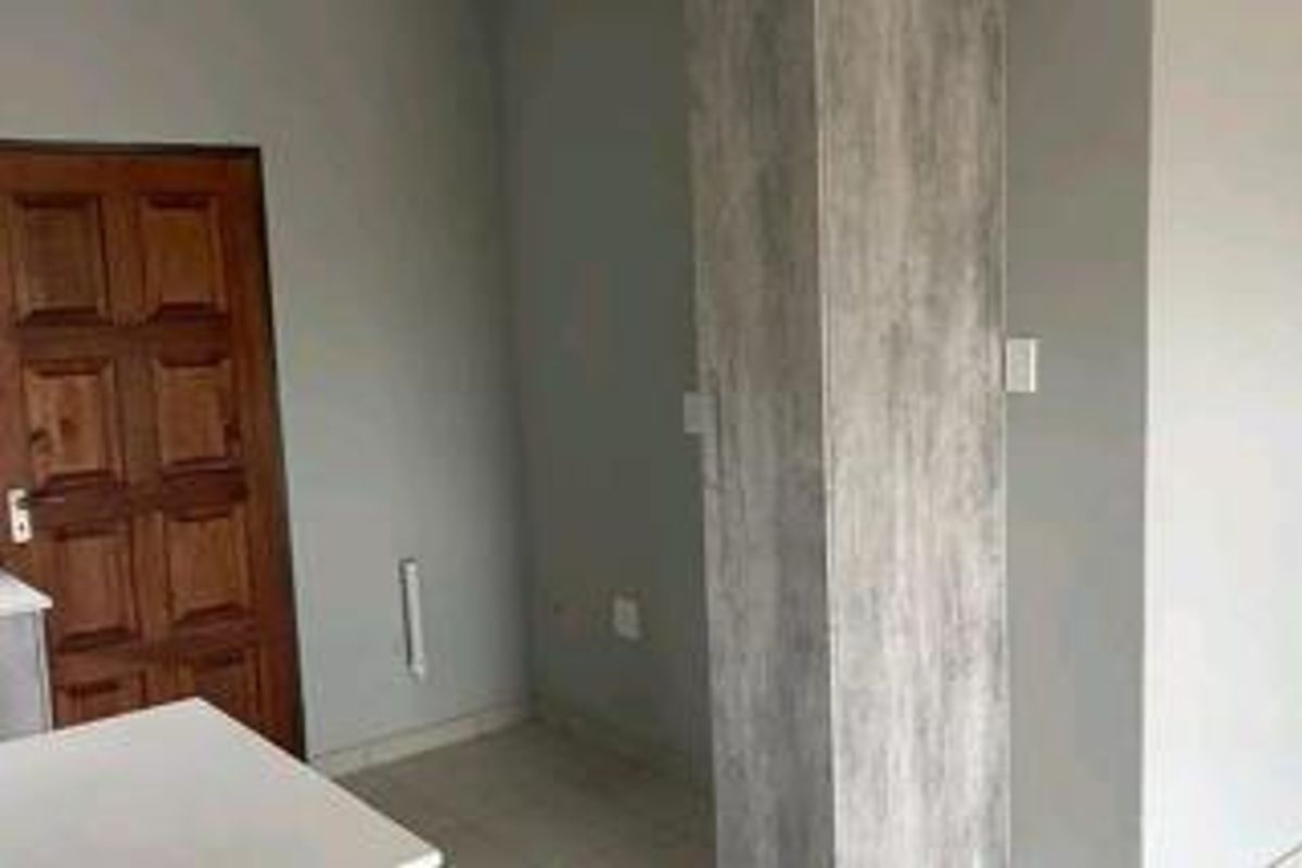 An empty bedroom featuring a wooden door and a built-in cupboard with a grey wood-look finish.