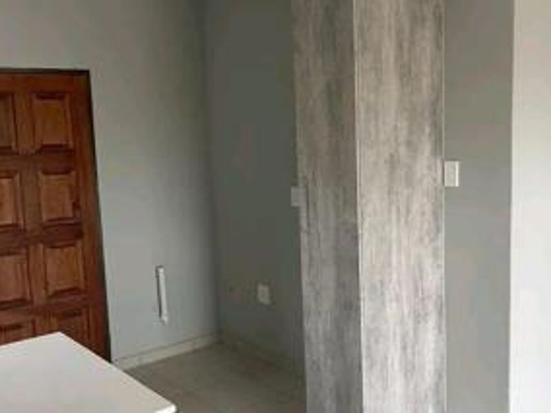 An empty bedroom featuring a wooden door and a built-in cupboard with a grey wood-look finish.