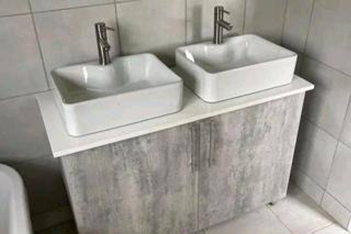 A modern bathroom vanity featuring a double vessel sink setup with chrome mixer taps and contemporary grey cabinetry.