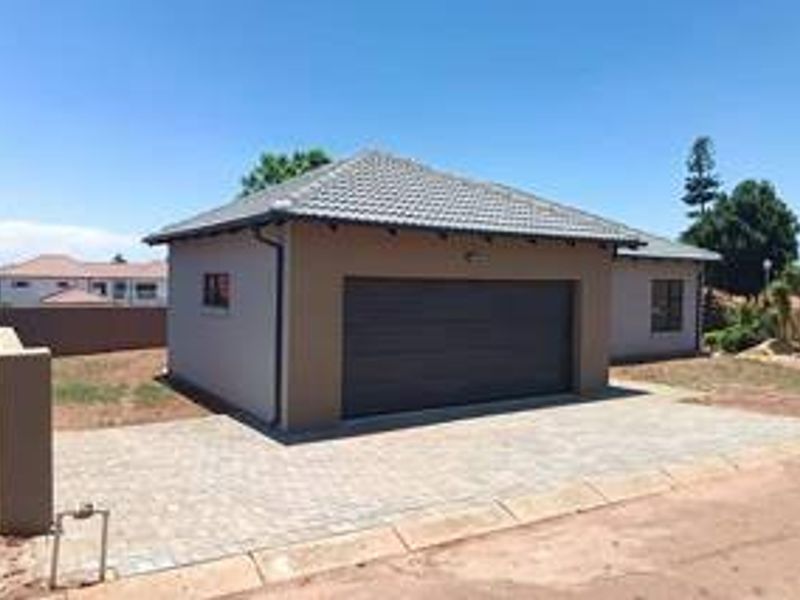 A detached garage featuring a tiled roof, a modern sectional door, and a paved driveway, set within a residential property.