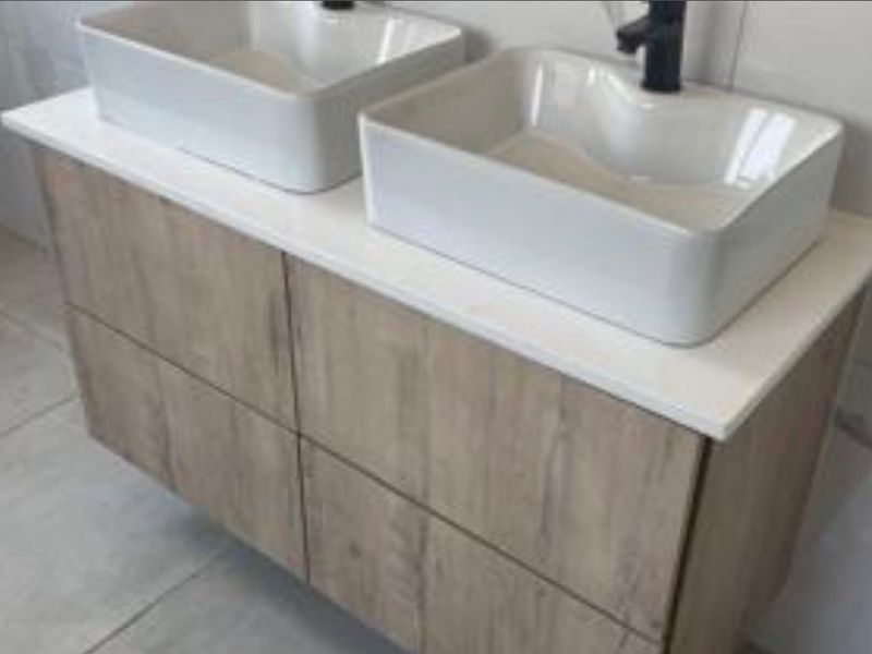 Modern bathroom vanity featuring a double vessel sink setup with wood-look cabinetry and black fixtures.