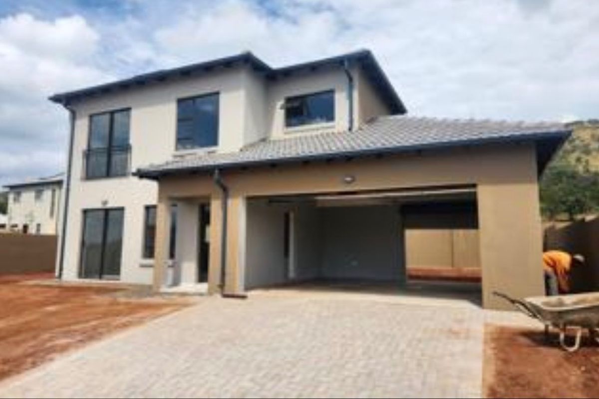 Modern double-story residential home featuring a double garage, paved driveway, and contemporary architectural finishes, currently undergoing final exterior landscaping.