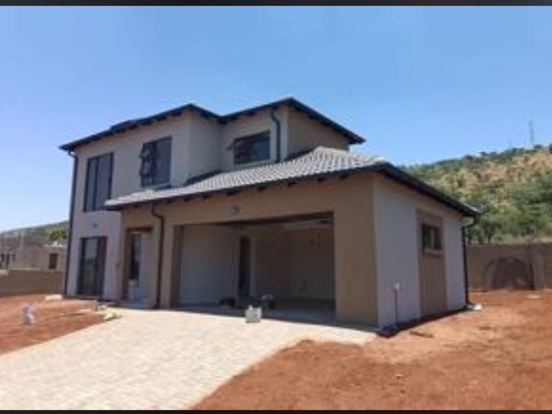 A modern double-storey residential house featuring a paved driveway, integrated garage, and neutral exterior finishes, set on an unlandscaped plot.