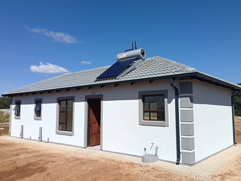 A modern single-story house exterior featuring a tiled roof, solar water heating system, and clean white facade with grey trim detailing.